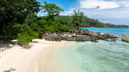 Secluded beach with crystal clear water and lush greenery. Seychelles.