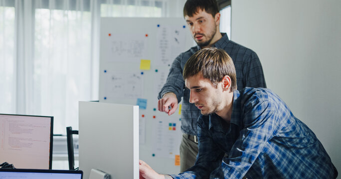 Team adult male engineer collaborate on robotic hand project using AI code solutions machine learning at tech workspace. Artificial intelligence interface, collaboration support prototype development.