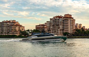 Obraz premium Motor boat yacht floating to marina. Luxury yacht boat at Fisher island. Summer vacation. Fisher island residential building and luxury yacht boat. Trip to Fisher island on yacht, Miami
