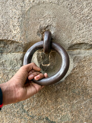 A hand is holding a metal ring that is attached to a wall