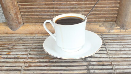 a glass of warm coffee served on a bamboo table