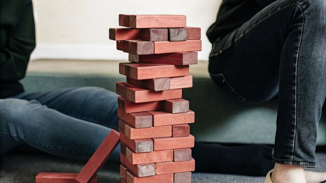 Close up wooden jenga toy block tower unstable structure tension concept falling moment background