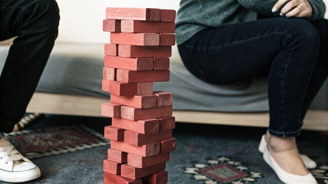 Close up wooden jenga toy block tower unstable structure tension concept falling moment background