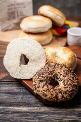 Closeup view of a variety of kinds of bagel breads with sliced bagel bread on a wooden board