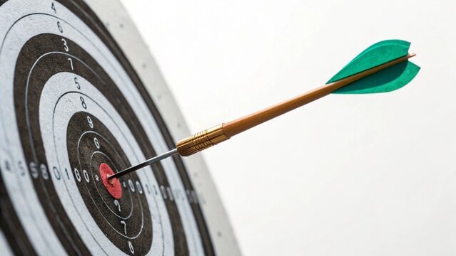 Close up green arrow hitting center target bullseye concept of achievement direction ambition goal white background