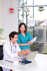 Asian Doctor and Nurse Discussing Patient Care on Laptop in Clinic Office Medical Team Collaboration Healthcare Professional