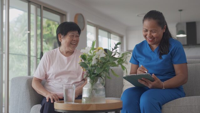Asian health care worker visiting elderly woman at home, home nurse, home care service concept