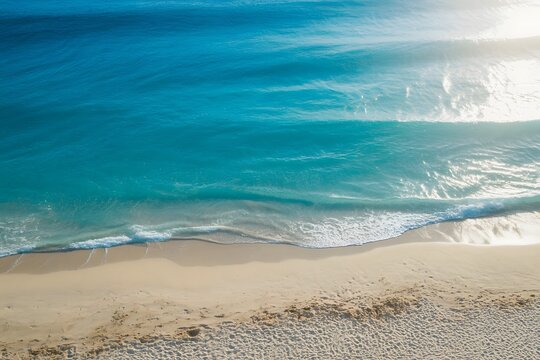 Aerial View of Turquoise Ocean Waves Crashing on Sandy Beach Shoreline