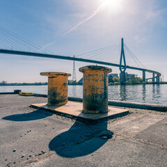 Die Köhlbrandbrücke in Hamburg im Hintergrund und zwei gelbe Poller, Festmacher im Vordergrund, 1:1