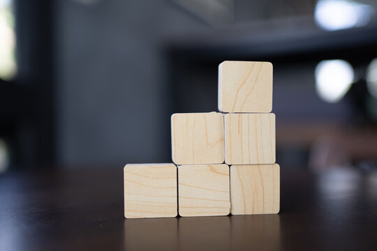 Wooden blocks stacked in pyramid shape on reflective surface with blurred background, business growth concept, building success, teamwork and leadership