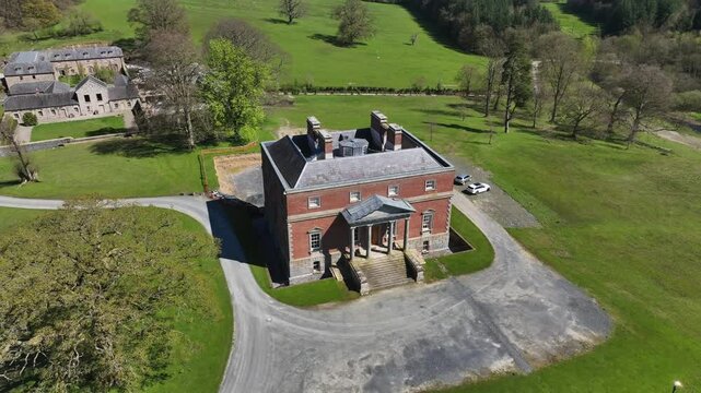Bellamont House, County Cavan, Ireland, April 2023. Drone pullback from historic red-brick mansion, estate grounds and scenic countryside aerial view on sunny day.