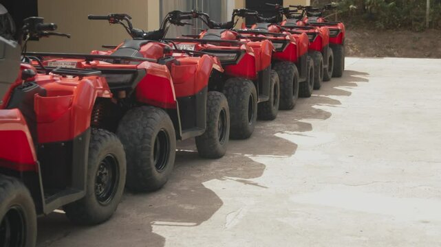 A group of red ATVs parked in line under daylight, ready for an offroad adventure tour.