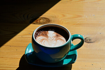 Close up view of hot chocolate with latte art in the green gauze cup. Wooden table, black, dark, shadow. copy space, empty, free.