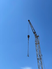 Metal crane at construction site with blue sky background