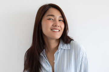 Asian woman smiling gently in light striped shirt isolated over white background wall.
