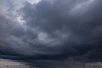 Heavy rain storm clouds building background backdrop with late evening sunlight shining through the clouds.