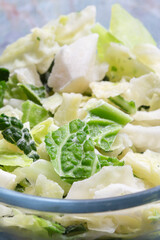 Frozen sliced cabbage defrosting in a glass bowl background backdrop. On a green marble background.