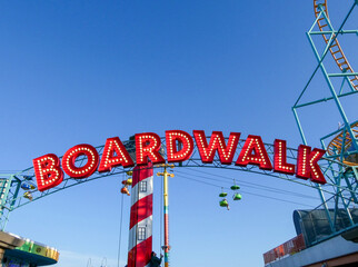 A red beach boardwalk sign against a blue sky © Val