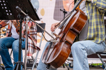 Musicians sitting on stage perform a live cello and violin duet, showcasing their musical talent....