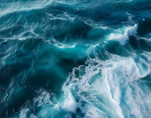 Powerful aerial view of vibrant turquoise and deep blue ocean waves crashing and swirling, creating a dynamic abstract pattern of sea foam and water movement.