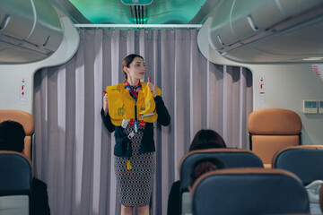 he flight attendant on the plane demonstrates the safety rules on the plane in a professional...