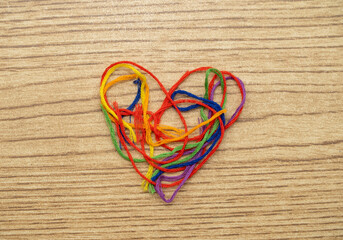 corazón de hilos de colores sobre mesa de madera