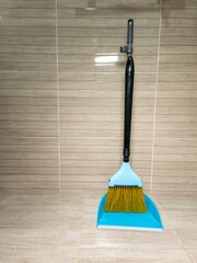 A broom and dustpan on a tiled floor in a bathroom