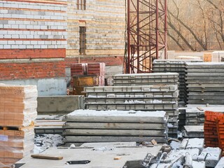 Construction site featuring a crane, concrete slabs, and building materials, under construction.