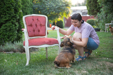 Woman painting a wooden furniture while sitting with her dog in the garden. DIY concept.
