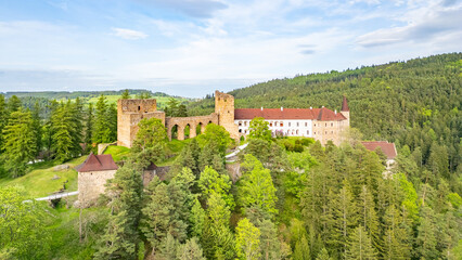 This aerial view captures Velhartice Castle nestled among lush forests in the Czech Republic. The historic site showcases impressive architecture and beautiful natural surroundings.