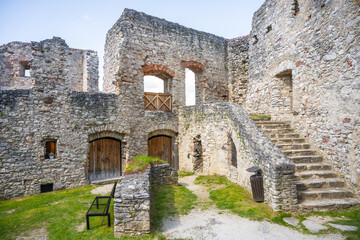 Visitors wander through the historic courtyard of Rabi Castle in Czechia, admiring the ancient stone walls and remnants of architecture under a clear blue sky.