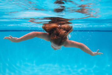 Underwater child swims in pool, healthy child swimming and having fun under water.