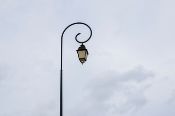 Vintage lamp post stands elegantly against a cloudy sky in a charming urban setting