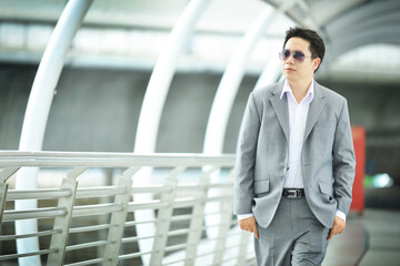 Asian businessman walking on a bridge outside office background