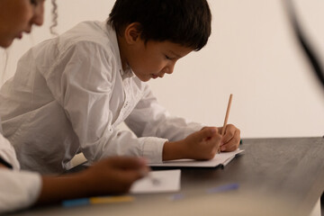 Elementary school student drawing on notebook with pencil