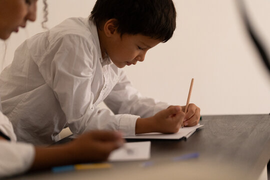 Elementary school student drawing on notebook with pencil