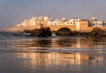 Essaouira, Morocco: Dramatic reflection of the famous ancient fortified walls of the Mogador old town in an atlantic ocean beach in Essaouira, Morocco