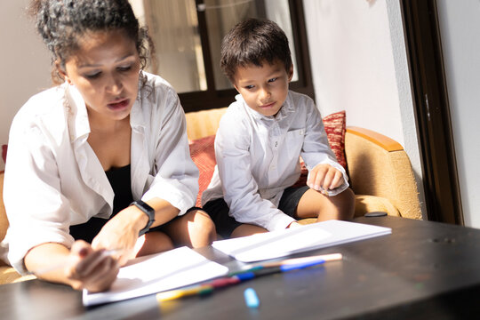 Mother helping son with homework, homeschooling during quarantine - Powered by Adobe
