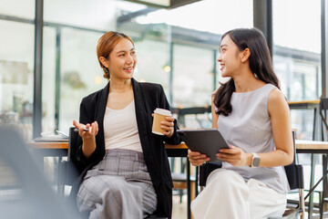 Fototapeta premium Young Asian business two women explain working together using documents tablet at the office. 