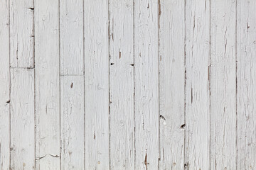 A white wooden wall with a lot of holes and cracks