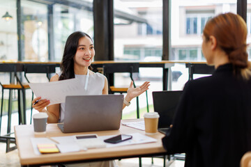 Two asian lady colleagues discussing new project, business asian women using digital tablet together in office
