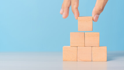 man is placing blank blocks in a row on the blue background