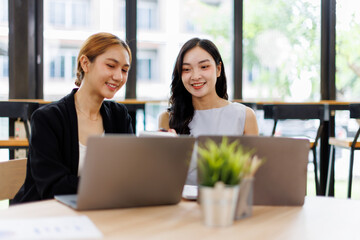 Two Asian company employees and colleagues teamwork discussing  together in the office. by talking and giving advice to each other
