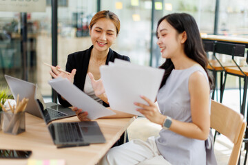 Two Asian company employees and colleagues teamwork discussing  together in the office. by talking and giving advice to each other
