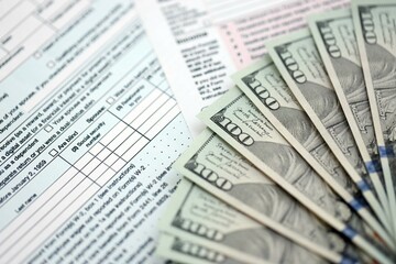 Big amount of United States dollar bills on table with tax return form close up