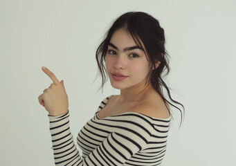 Happy Young Woman Pointing to the Side – Studio Portrait with Striped Top, Tattoo Detail, White Background, High-Resolution Stock Photo with Copy Space for Advertising and Marketing