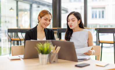 Two managers discussing contract in meeting room or modern office workplace.Two young pretty asia business woman work.