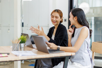 Fototapeta premium Two managers discussing contract in meeting room or modern office workplace.Two young pretty asia business woman work.