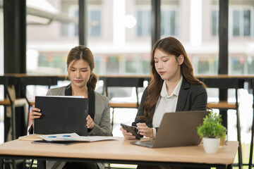 Asian businesswoman sitting in a meeting, talking about a document and chart placed on the table.