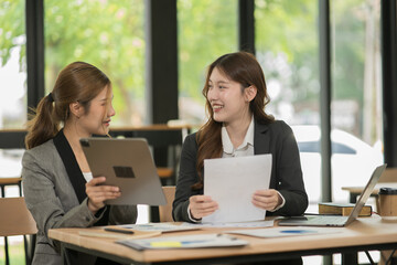 Asian businesswoman sitting in a meeting, talking about a document and chart placed on the table.